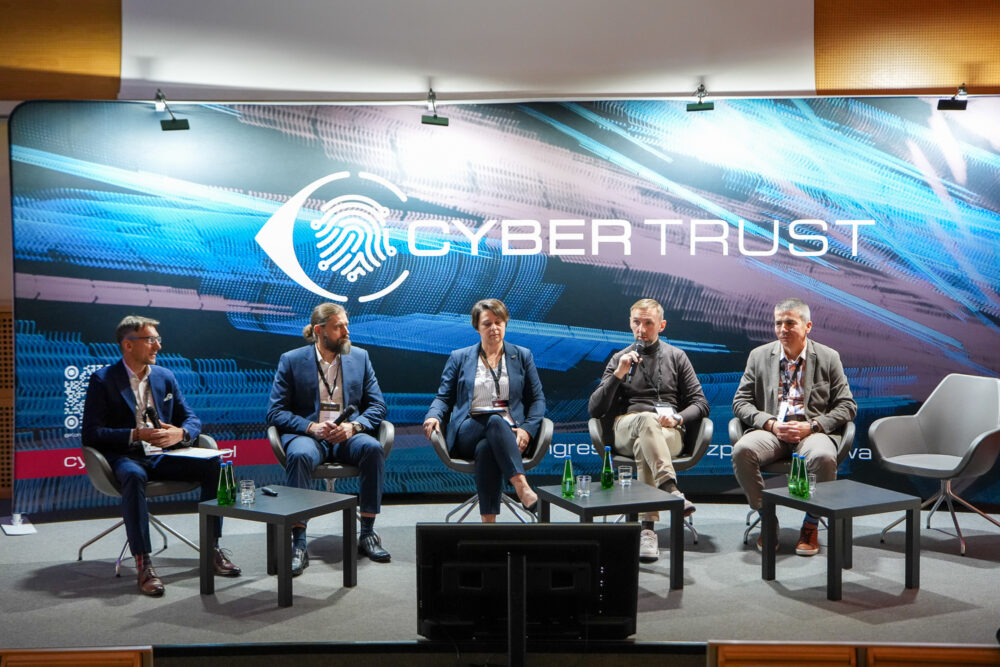 Kongres Cyberbezpieczeństwa CyberTrust 2026 - uczestnicy debaty siedzą na fotelach na scenie głównej, w tle logo CyberTrust